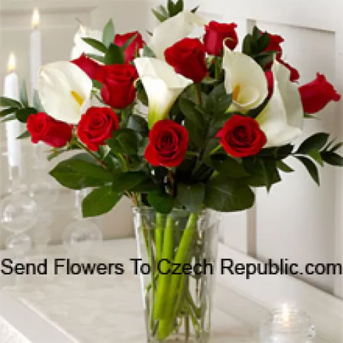 Punaiset ruusut ja valkoiset liljat muutamilla saniaisilla lasimaljakossa