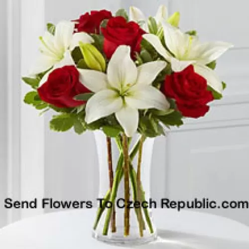 Trandafiri roșii și crini albi cu niște umpluturi sezoniere într-o vază de sticlă